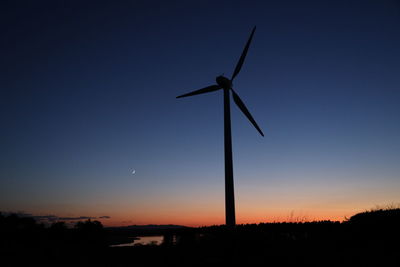 Low angle view of wind turbines on field against sky