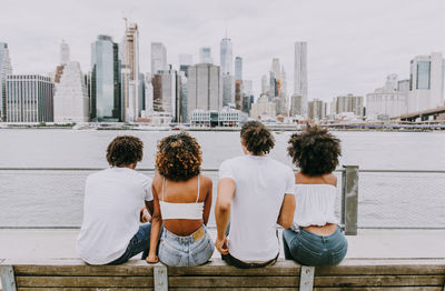 Rear view of friends looking at cityscape by river