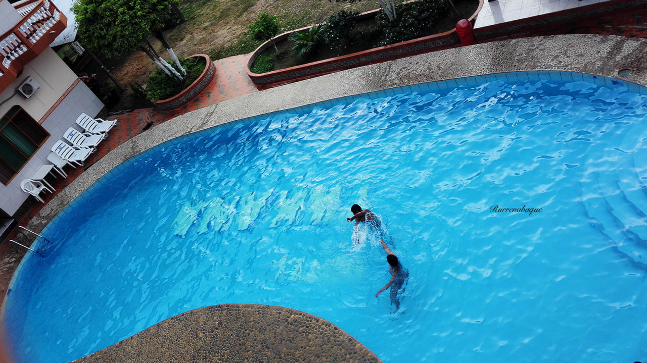 HIGH ANGLE VIEW OF A MAN SWIMMING IN POOL