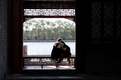 Rear view of people sitting on bench looking at view