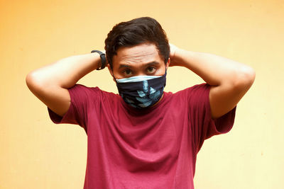 Portrait of young man standing against wall