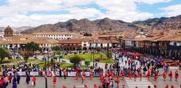 People on street by buildings in town against sky