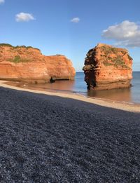 Rock formation on beach against sky