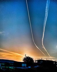 Low angle view of vapor trails against sky at sunset