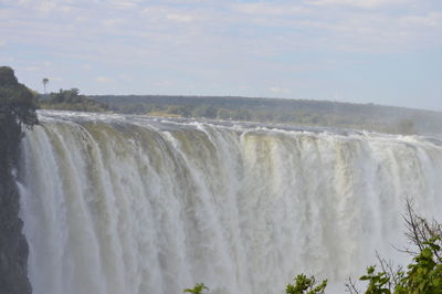 Scenic view of waterfall against sky