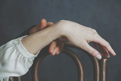 Cropped hands of couple on chair against wall at home