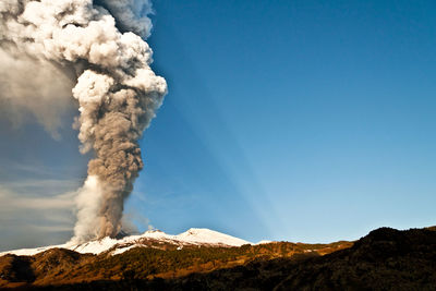 Smoke emitting from volcanic mountain against sky