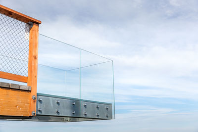 Low angle view of railing by sea against sky