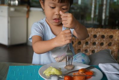 Close-up of girl eating food at table