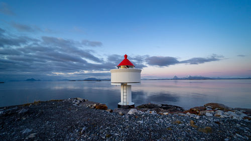 Lighthouse by sea against sky