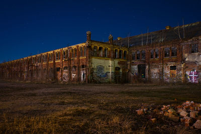 Old building against clear blue sky at night