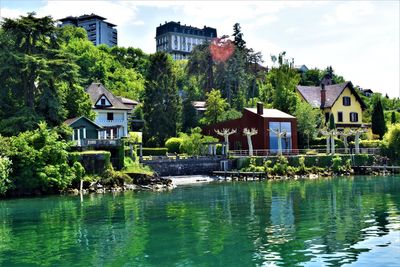 Houses by lake and buildings against sky