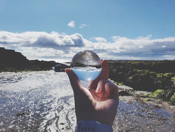 Midsection of person holding sea against sky