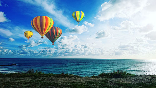 Hot air balloons flying over sea against sky