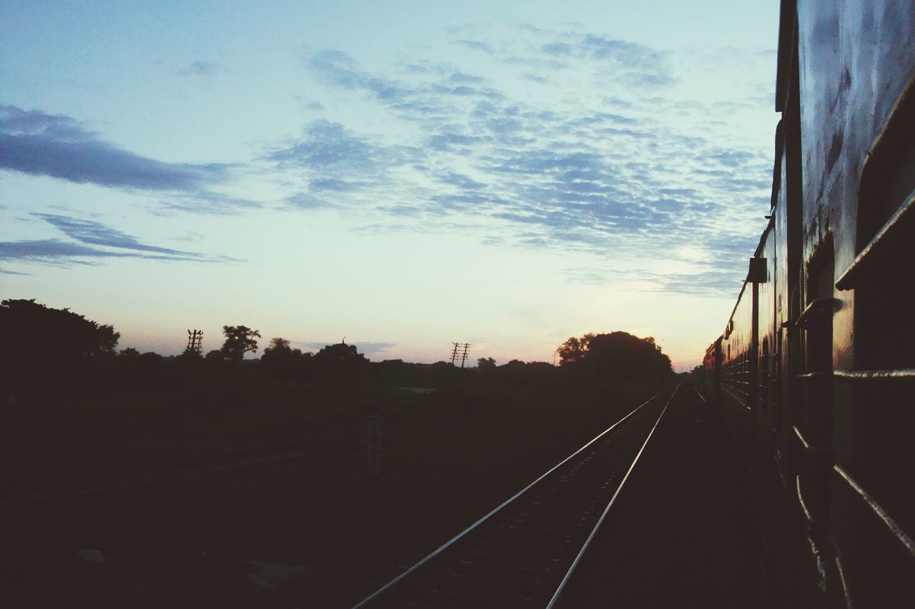 railroad track, transportation, sky, the way forward, rail transportation, built structure, architecture, diminishing perspective, vanishing point, building exterior, public transportation, cloud - sky, railway track, connection, railing, sunset, cloud, mode of transport, outdoors, silhouette