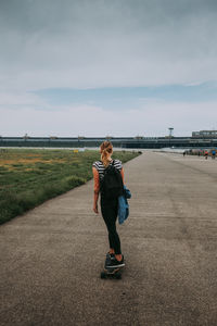 Full length of woman standing on road against sky