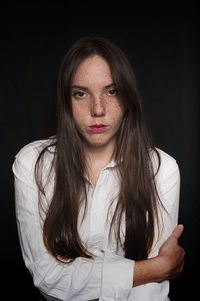 Portrait of woman with freckles against black background