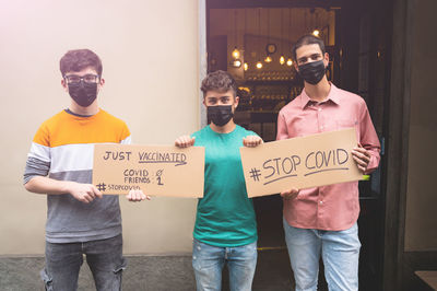 People wearing mask holding cardboard standing outdoors