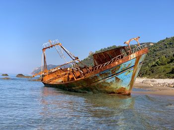 Abandoned fishing boat in sea against sky