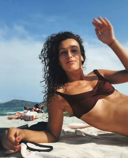 Beautiful young woman at beach against sky