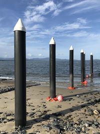 Wooden posts on beach against sky