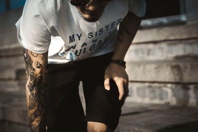 Midsection of tattooed young man wearing casuals in city