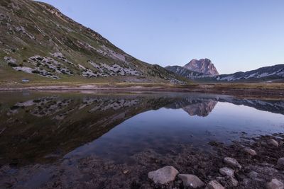 Scenic view of lake and mountains against clear sky during sunset