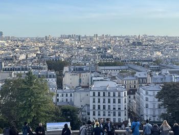 People on buildings in city against sky