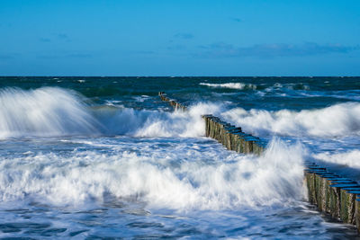 Waves splashing on shore against blue sky