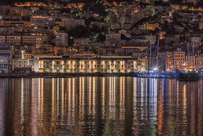 Illuminated buildings by sea at night