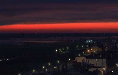 View of illuminated city against cloudy sky