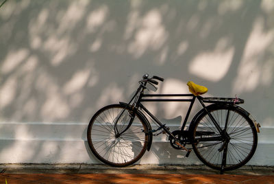 Bicycle parked against yellow wall