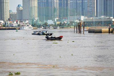 Boats in river against buildings in city