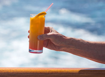 Cropped hand of man having drink on boat in sea