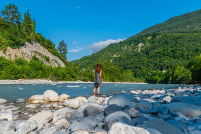 Man standing on rocks by mountain against sky