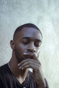 Close-up of young man looking away against wall