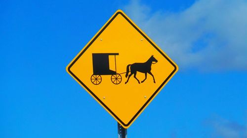 Low angle view of sign board against blue sky