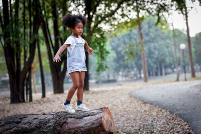 Full length of woman with arms raised against trees