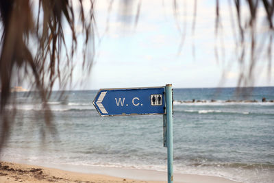 Information sign on beach against sky