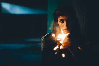 Portrait of woman with lit sparkler in darkroom