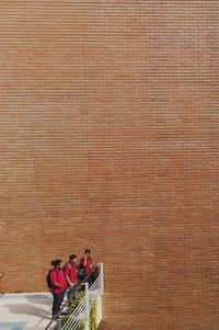 Friends standing in balcony against brick wall