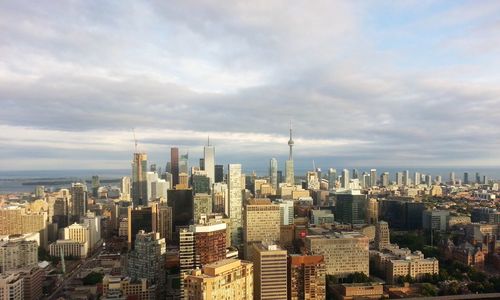 Cn tower amidst buildings against cloudy sky in city