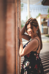 Portrait of young woman standing against built structure