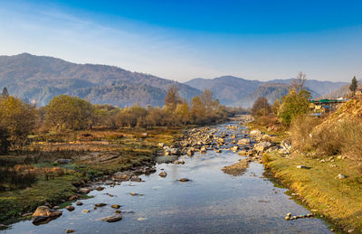 River flowing through misty mountain valley covered with dense forests and mist at dawn