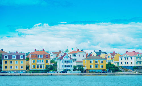 Buildings by river against blue sky