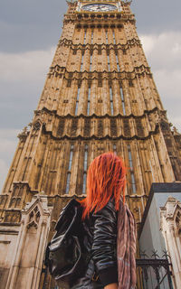 Low angle view of young woman standing against big ben