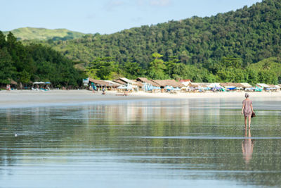 Rear view of woman walking on beach against sky