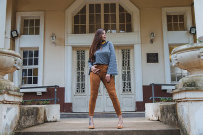 Full length of woman standing outside house