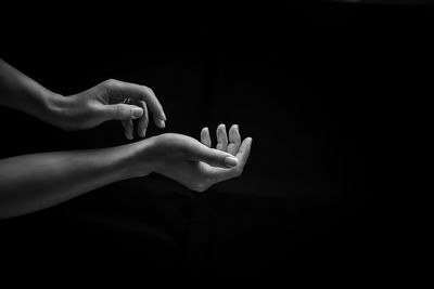 Cropped hands of woman against black background