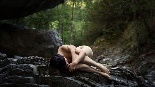 Young woman on rock in forest